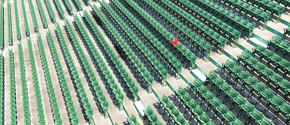 rows of green baseball stadium seats with one lone red chair