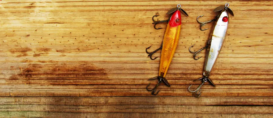 two fishing lures on a wooden surface