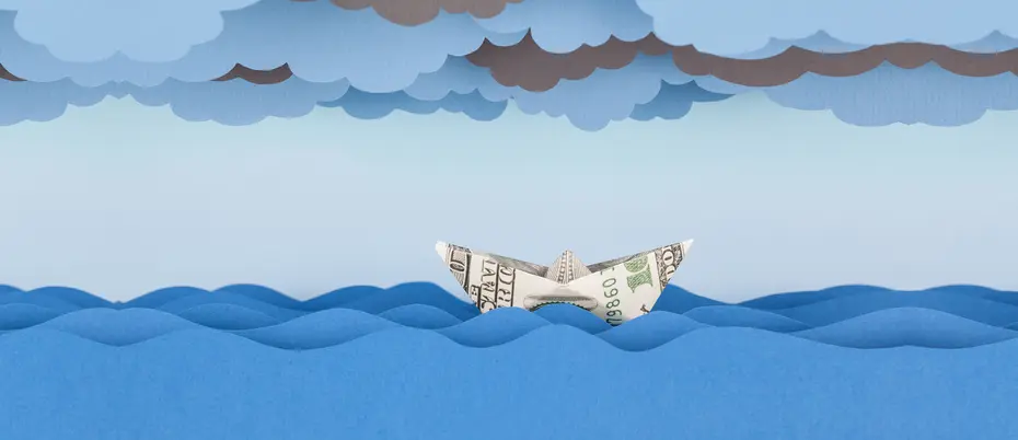 boat made of a dollar bill floating in a sea with clouds overhead