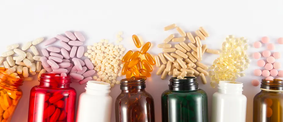 five brightly colored pill bottles on their sides with different sized pills spilling from each