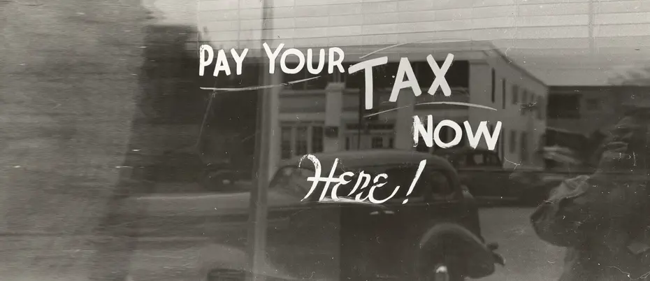 Black and white window sign that says pay your tax now here