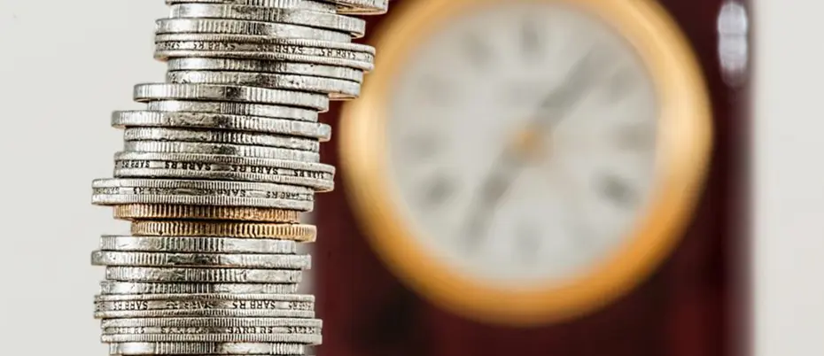 stacked coins with clock in background