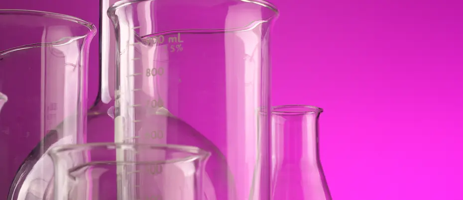 Glass laboratory beakers on fuchsia background.