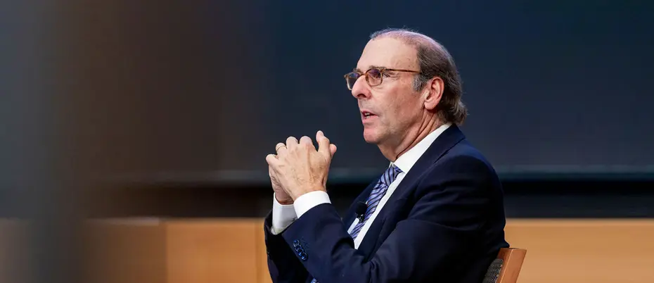 jim foster, seated, gestures to a crowd