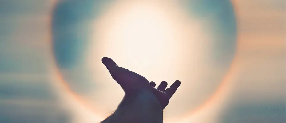 Silhouette of hand against a solar flare