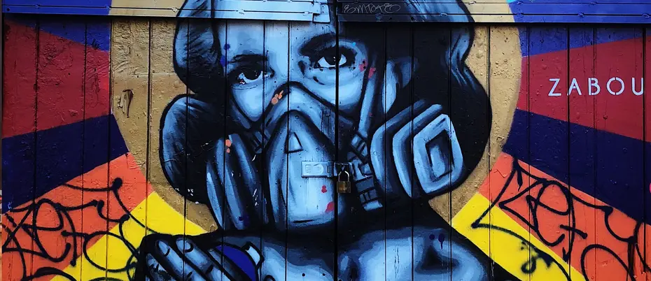A photograph of graffiti depicting a person wearing a facemask to protect themselves against contaminants in the air.