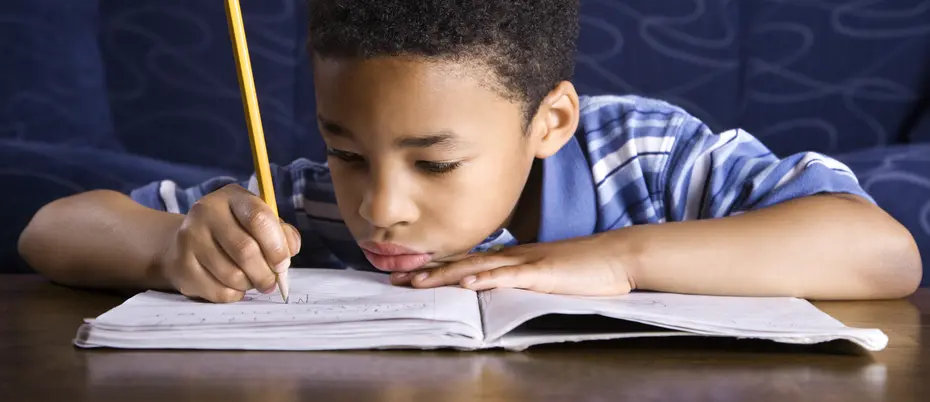 Child writing in book with a pencil