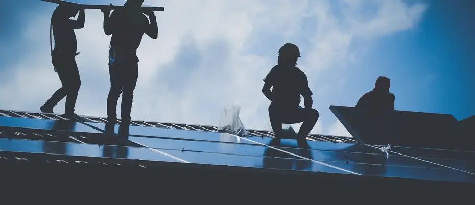 four people installing solar panels