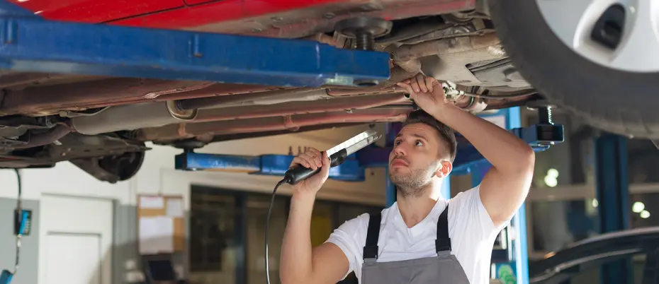 person standing underneath and fixing car 
