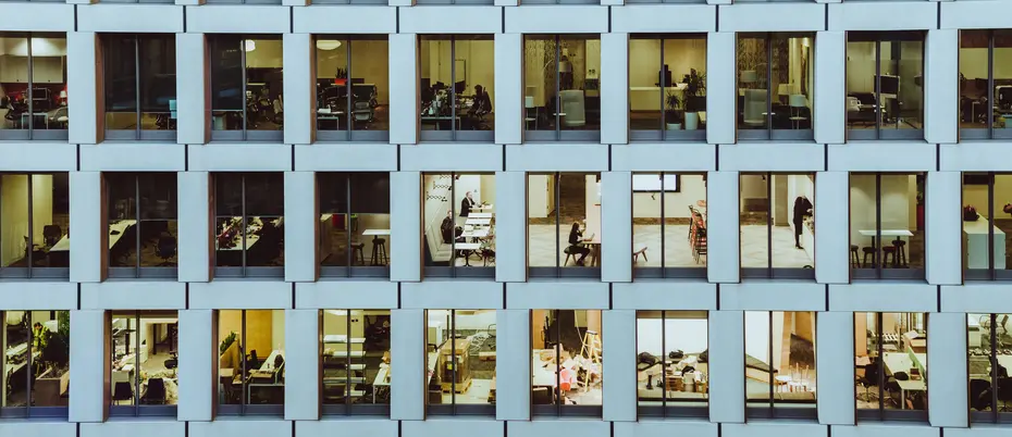 Photo of outside of a high-rise building with people working inside.