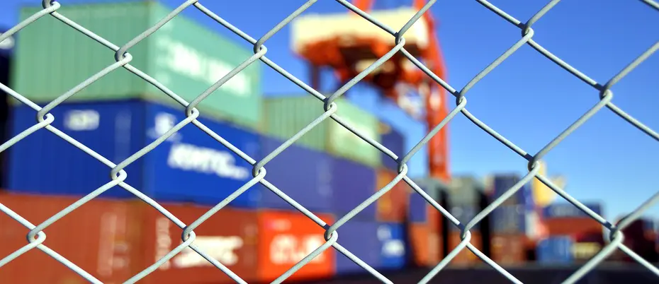 Photo of a container yard behind a chainlink fence to illustrate supply chain disruption.