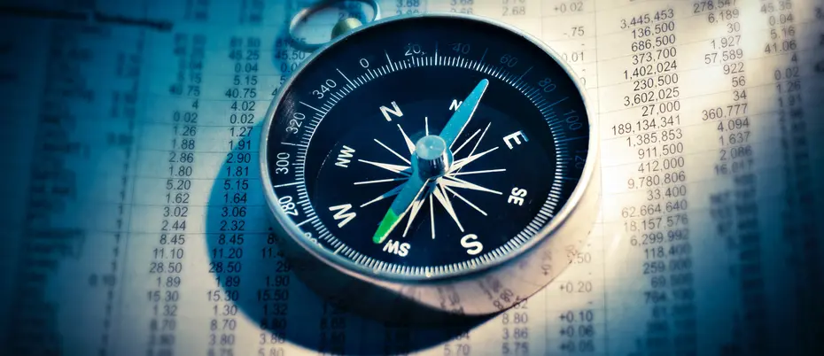 Compass sitting on top of stock market prices. 