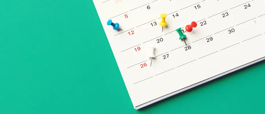 a wall calendar with colorful pins in it, meant to represent earnings timing