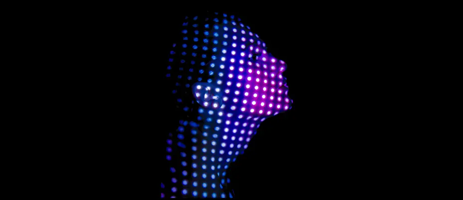 Woman's face covered in dots of light against a black background.