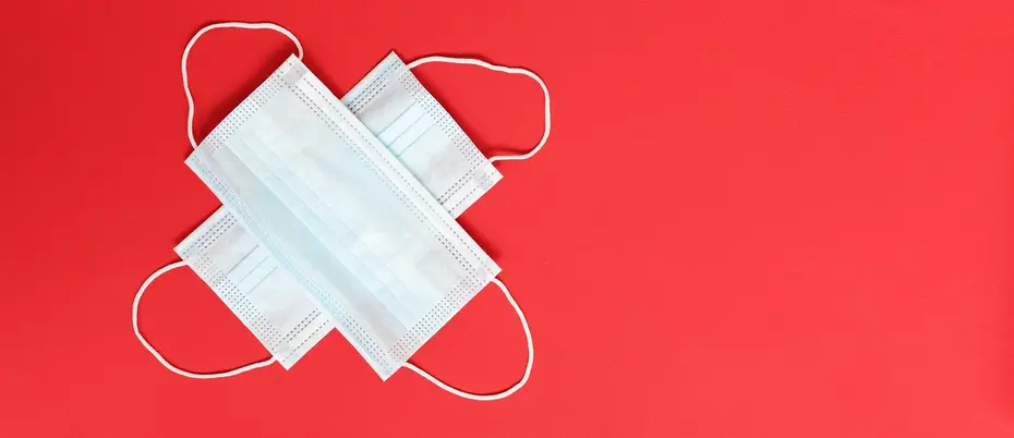 Two disposable COVID-19 face masks on an orange background