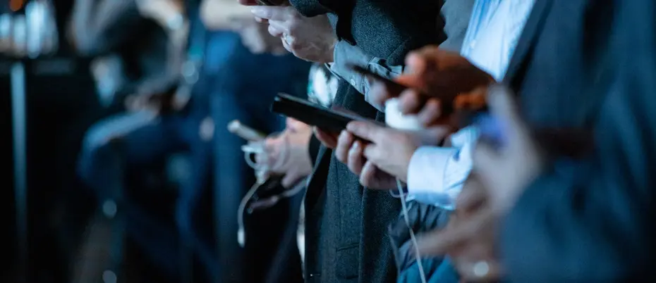 View of several people's hands as they look at and type on their smartphones.