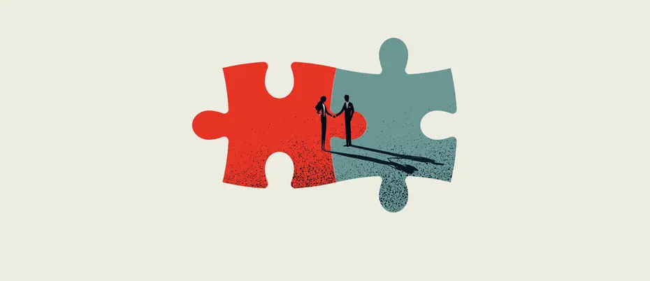 Two puzzle pieces joining, in the center are two business people shaking their hands