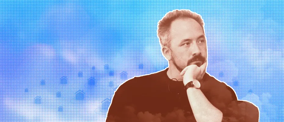 a man sits in a chair, his left arm bent and his left hand cupping his chin