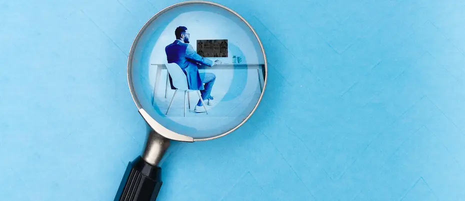 A magnifying glass looking at a worker at desk