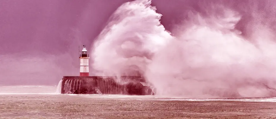 Huge waves crash over harbor sea wall and lighthouse