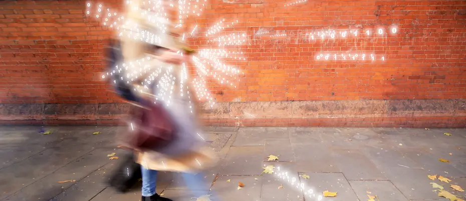 A person walks and emits binary code.