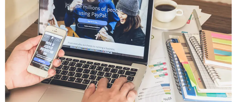User logging in to PayPal on cell phone and laptop