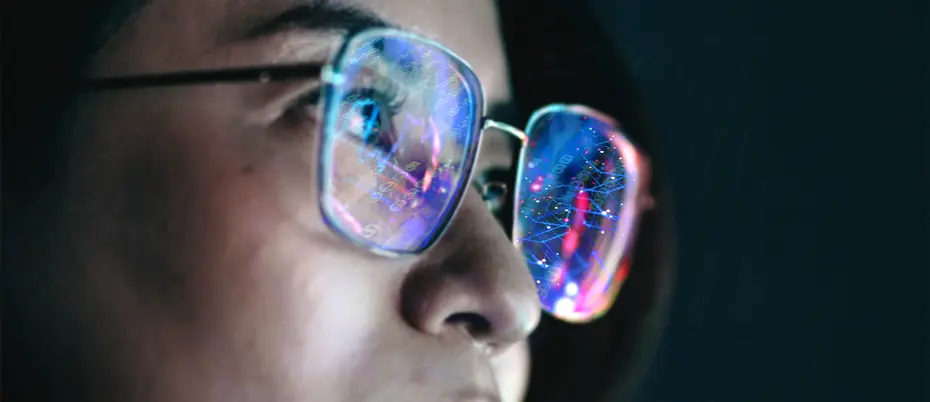 A person wears eyeglasses with lenses that reflect abstract digital art