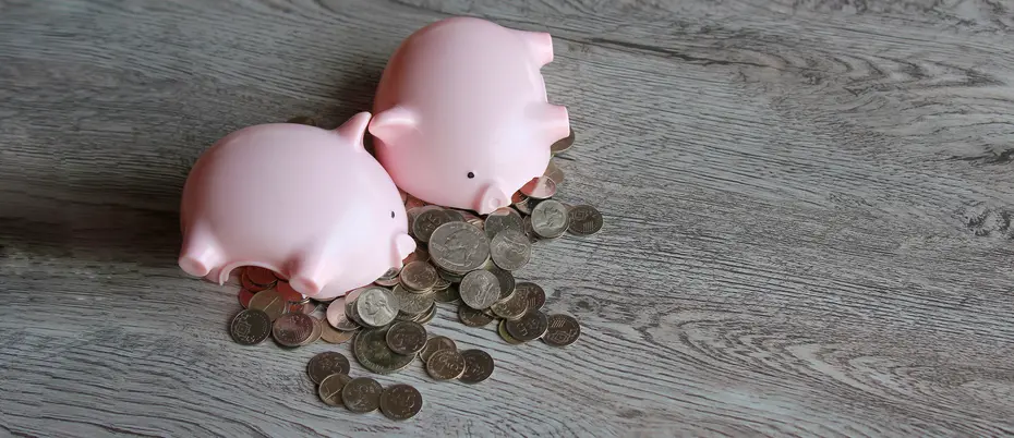 Two piggy banks lying down with coins spilling out