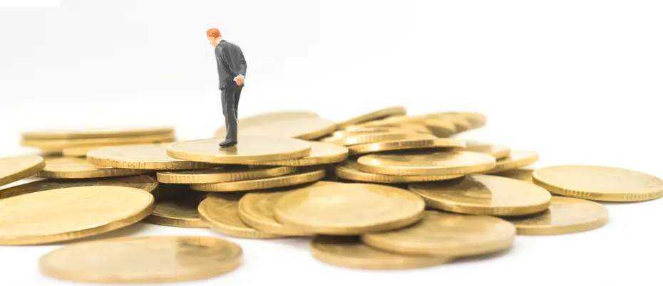 A business person thinking while walking on a pile of gold coins