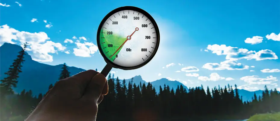 A person holds a magnifing glass with a carbon dashboard on it