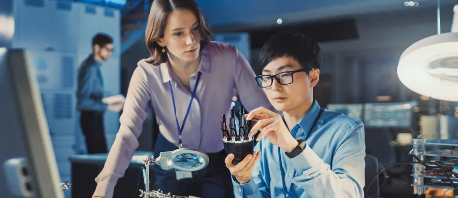 Workers look at a robotic arm in a laboratory
