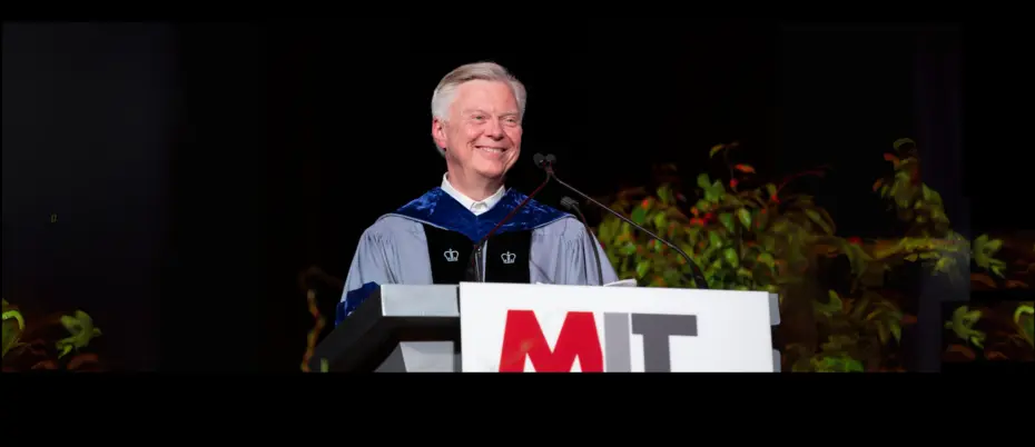 Dean Dave Schmittlein stands behind a podium in commencement regalia