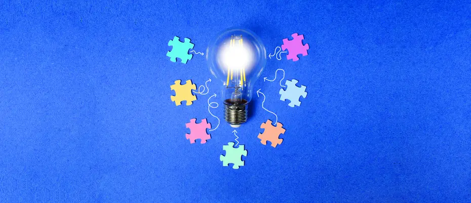 A lightbulb is surrounded by various colorful puzzle pieces