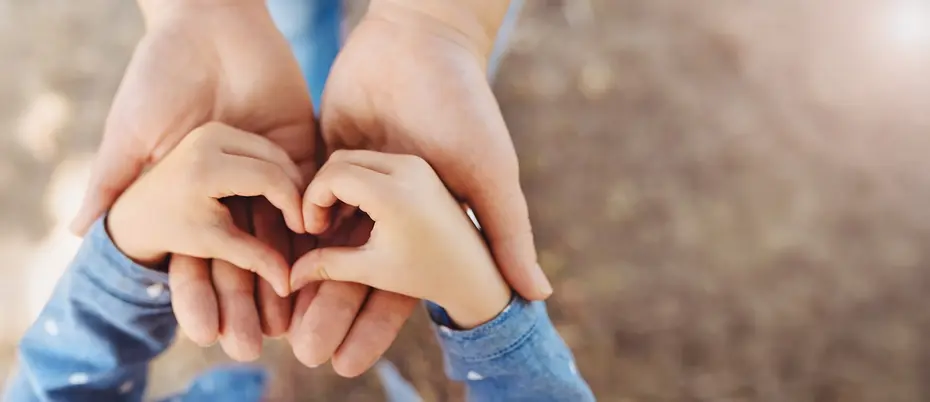 Adult hands holding child's hands in heart shape