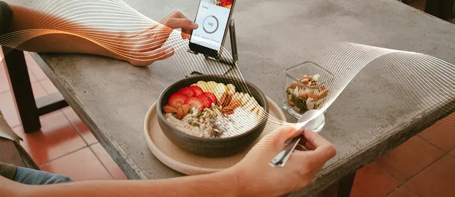 A person eats a healthy breakfast while looking at a phone app