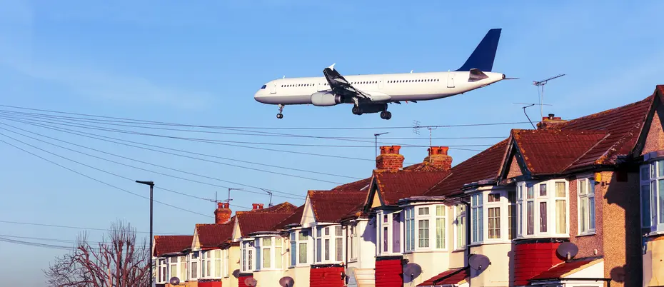 An airplane flies low over a neighborhood