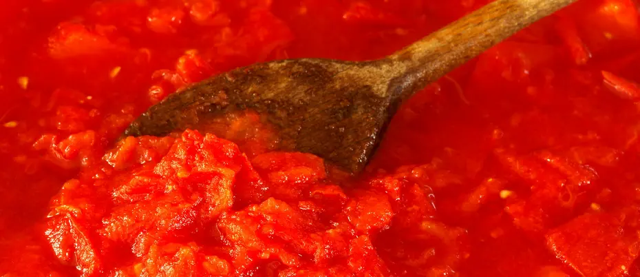 Tomatos simmering with a wooden spoon in the pot 