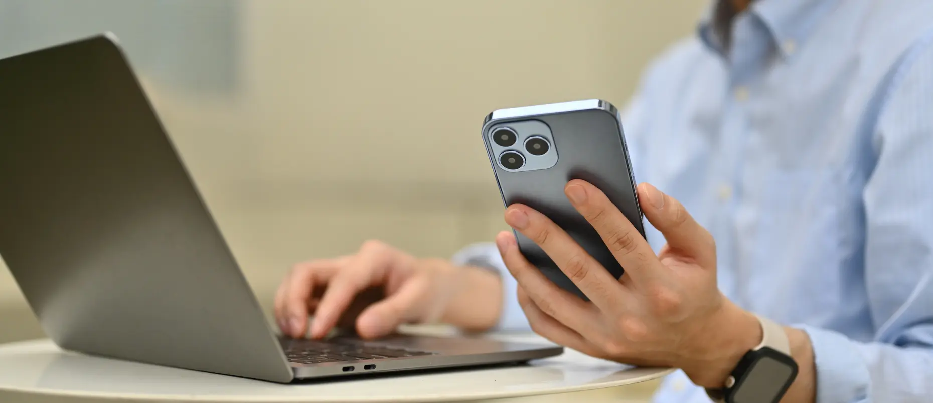 Close-up image of an unrecognizable businessman using a mobile phone and laptop, remotely working from outside
