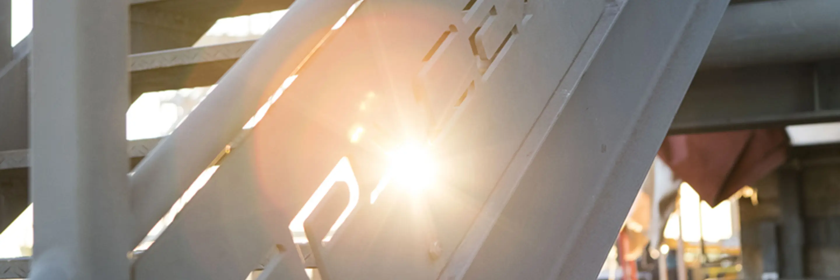 A railing with the sun shining through the SpaceX logo 