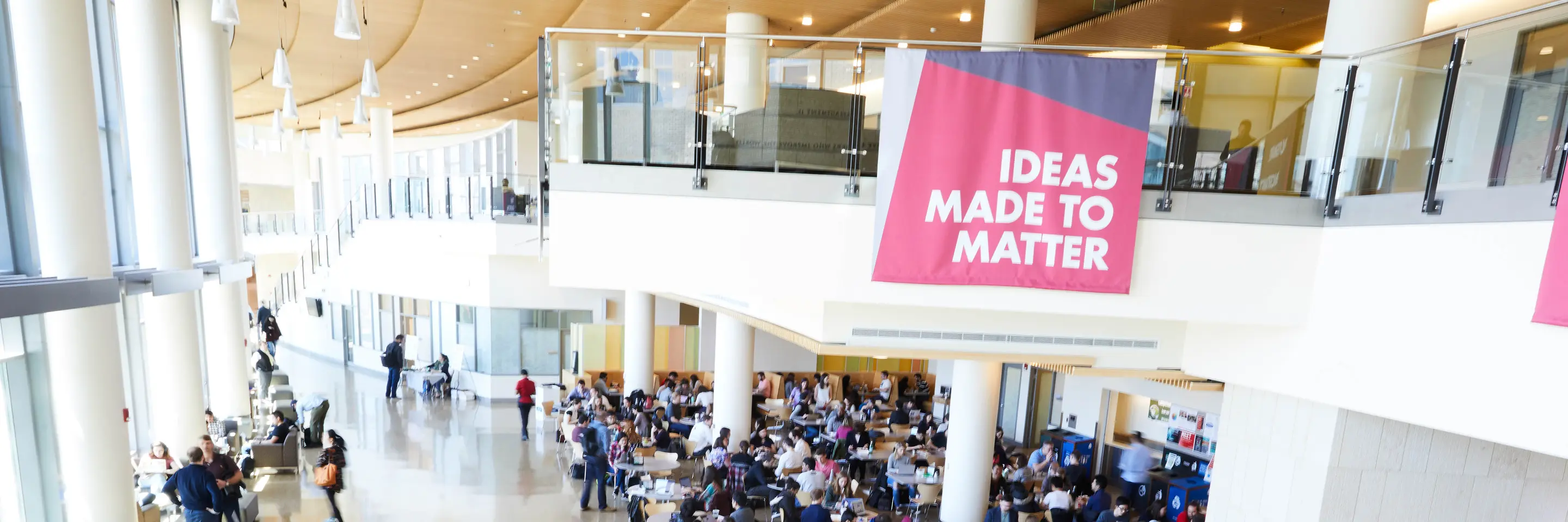Lobby of MIT Sloan building with students sitting at tables