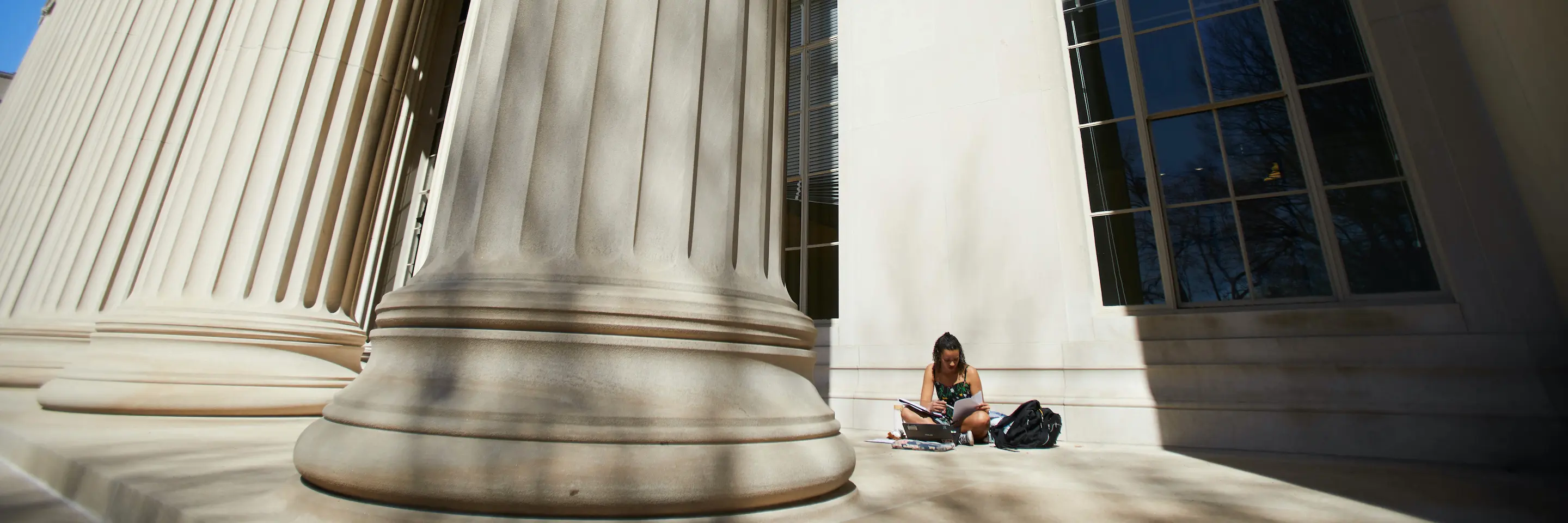  A women reading behind MIT's grand columns