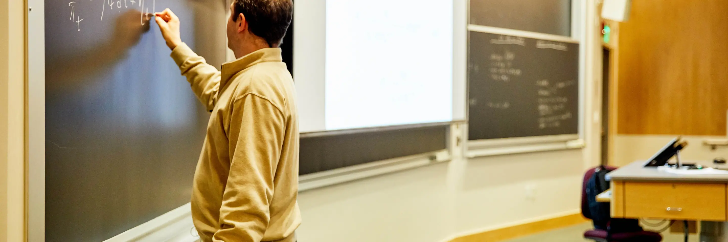A photo of a professor writing on a chalkboard