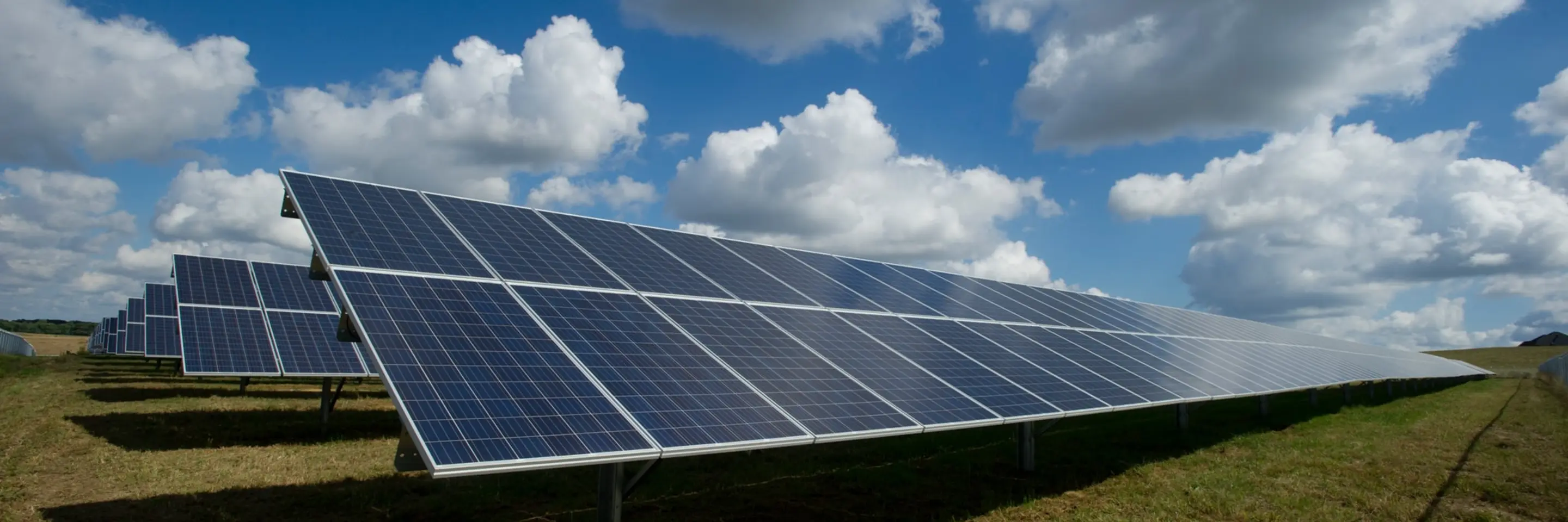 Solar panels in a field on a partly cloudy day