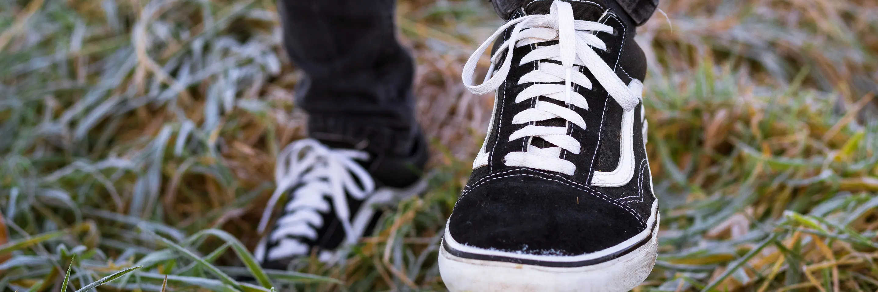 Close up of black sneakers on feet, standing on grass