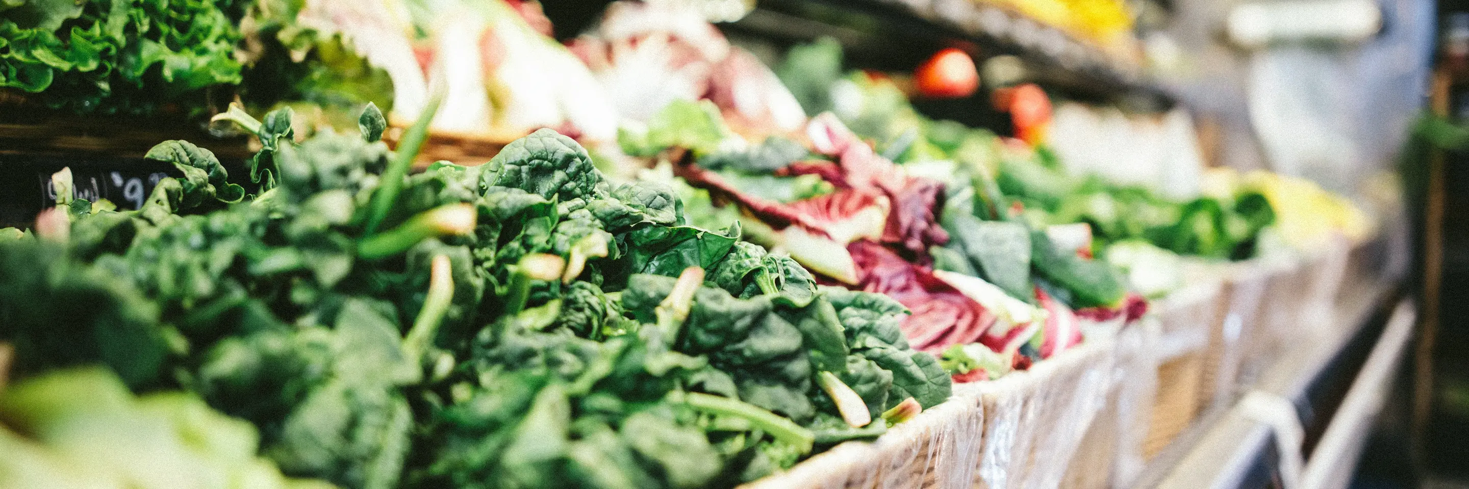 Market shelf with baskets of leafy produce