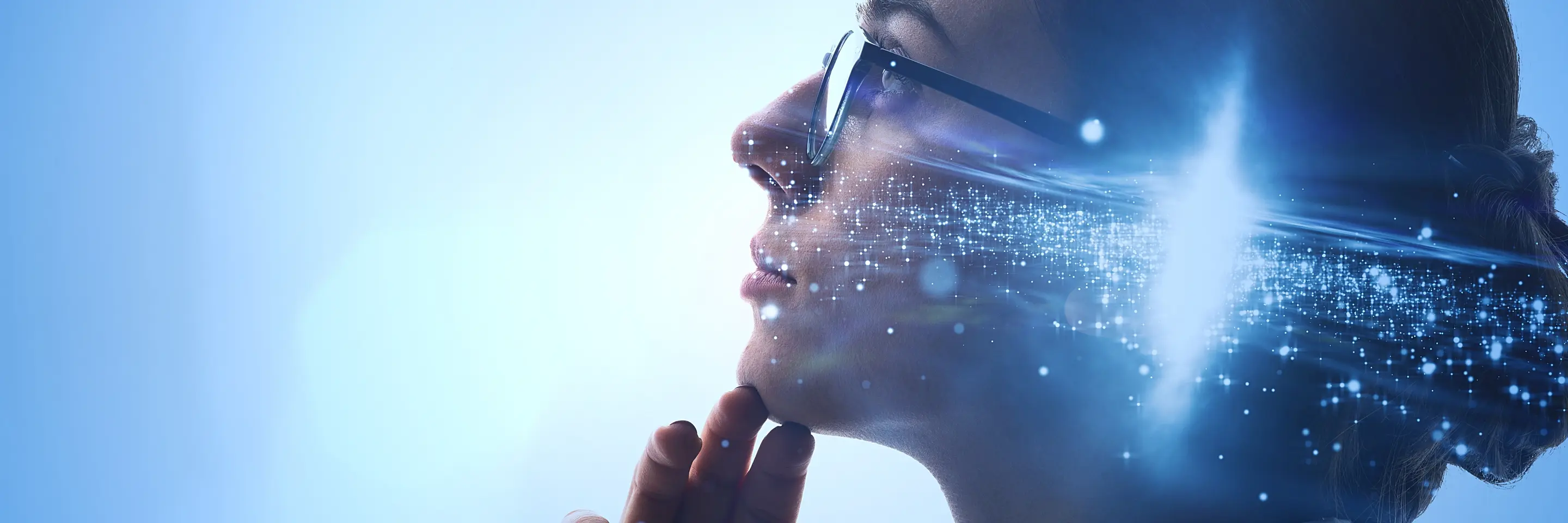 Side view of woman wearing glasses and a bun looking up with fingers on her chin. There is an image of a galaxy overlaid on her head.  