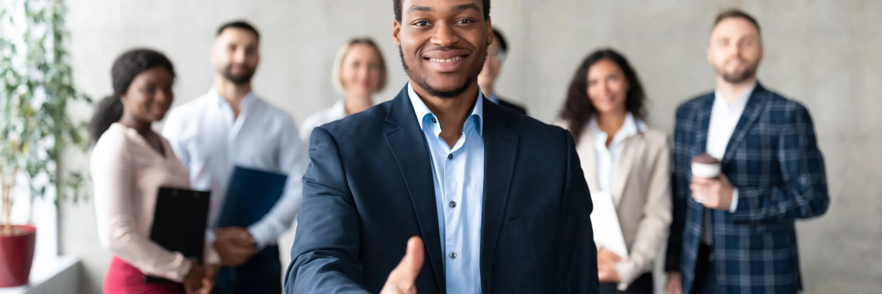 Business man extending his hand to you with a group of workers standing behind him