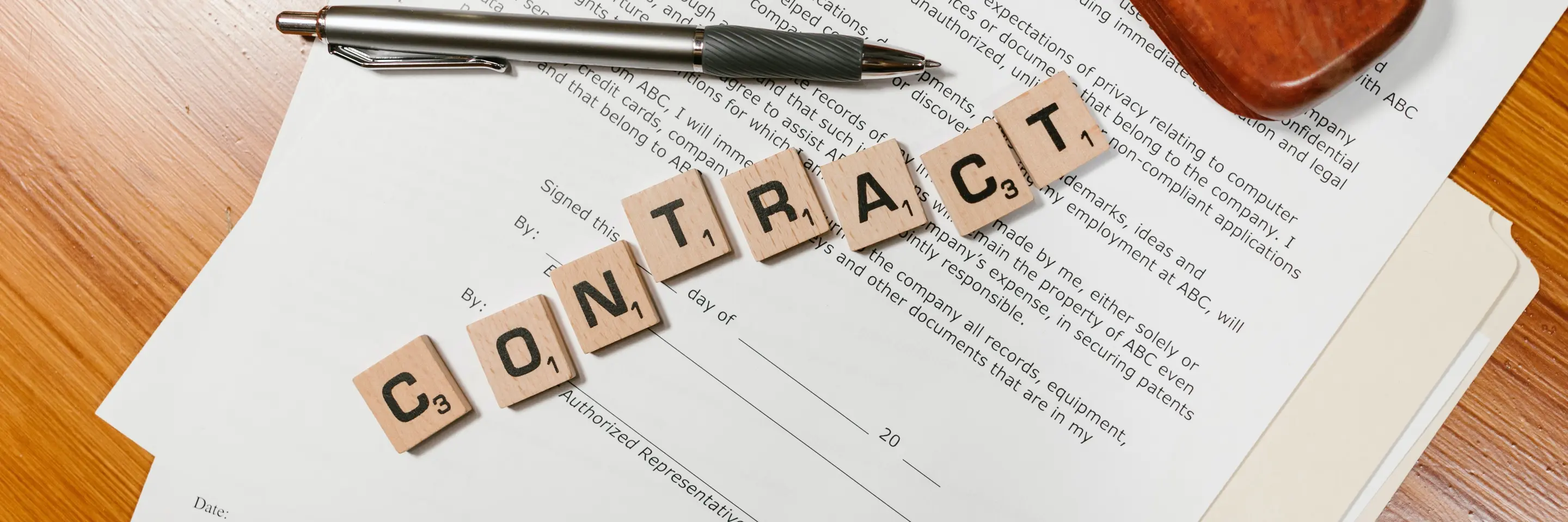 Image of a contract and office supplies, with the word "Contract" spelled out in Scrabble tiles