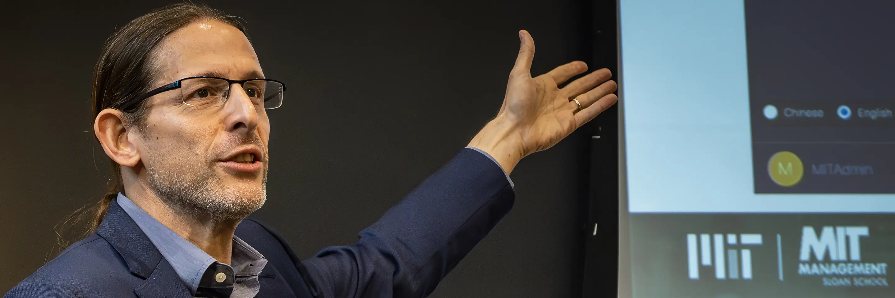 Man gesturing towards a slide on a projector.