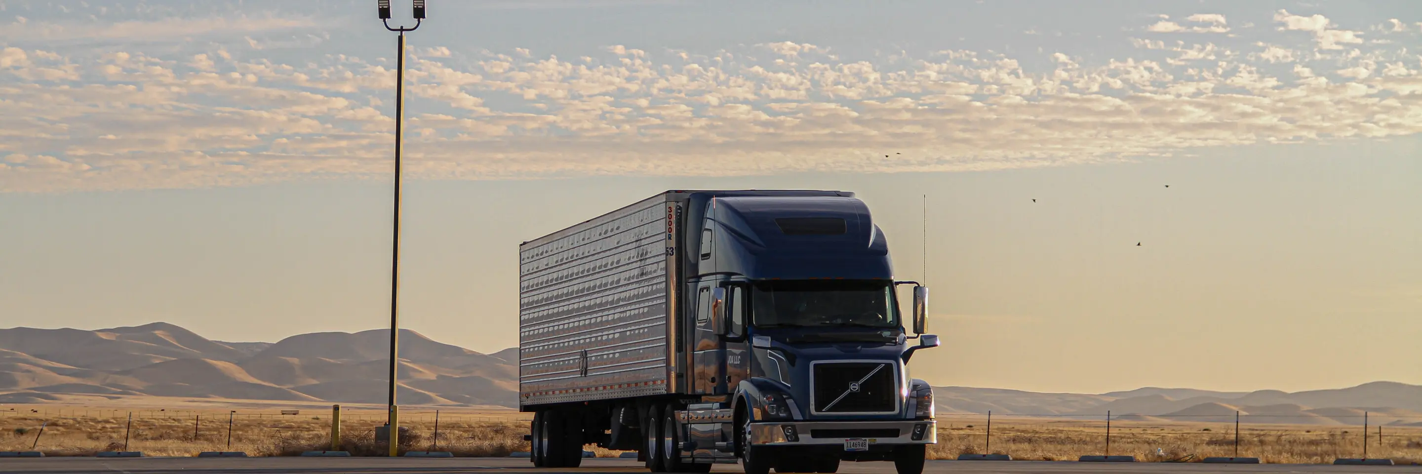 White freight truck on road with mountain range in the background.